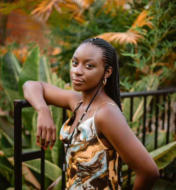 pexels-photo-9225150-9225150 A stylish woman with braids poses confidently outdoors, surrounded by lush greenery.