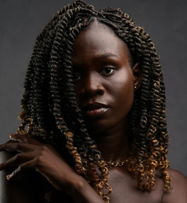 pexels-photo-9928018-9928018-1 Studio portrait of a woman with striking curly hair and a contemplative look.